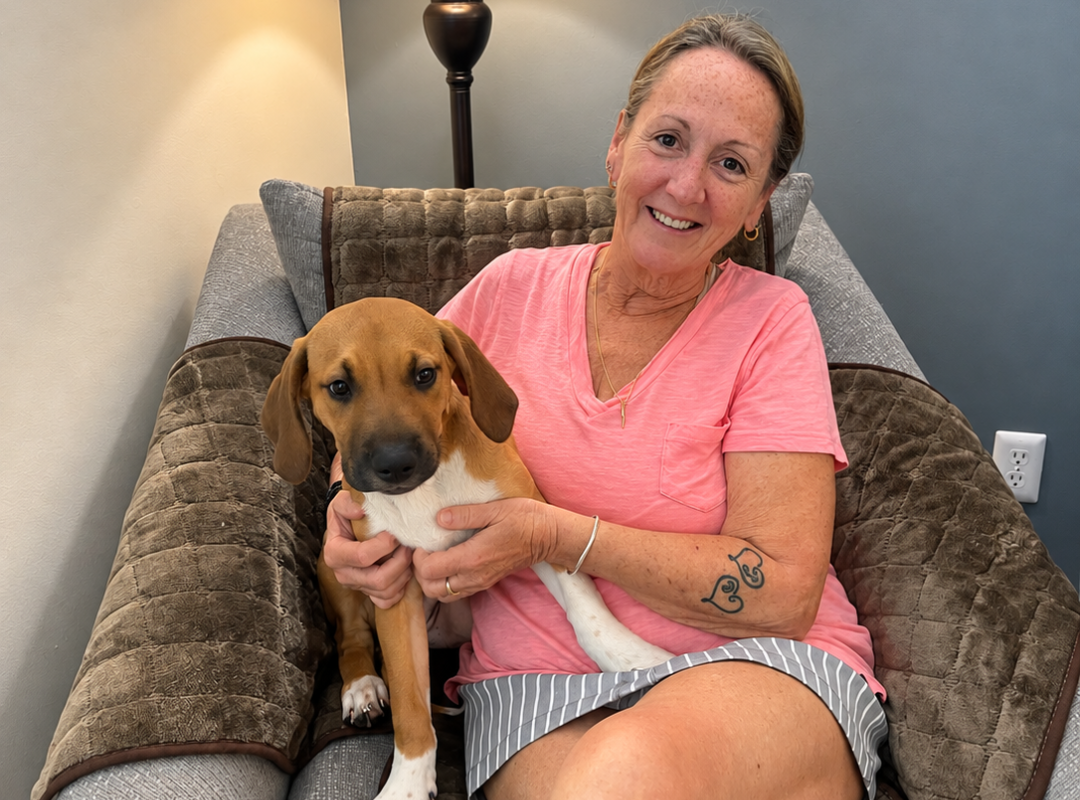 Patricia Cercone and her puppy smiling sitting in her home