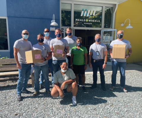 Durham Tactical group volunteers smile in front of Meals on Wheels Durham building.