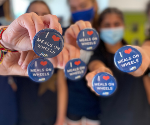 Students holding I Heart Meals on Wheels Buttons