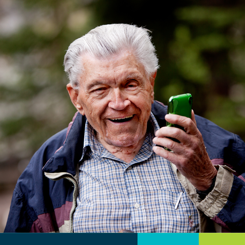 Senior gentleman smiling while holding his mobile phone.