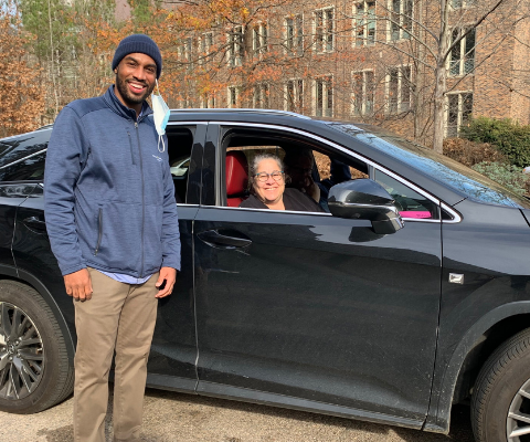 Jason Peace smiles with volunteer driver outside her vehicle.