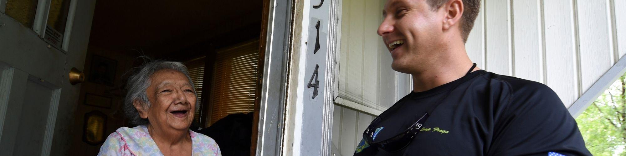 Volunteer and Client smile at door of client's residence.