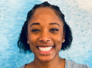 Asyia Robertson professional headshot smiling in front of a wall.