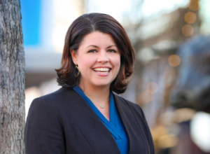 Tiffany Bashore professional picture smiling by a tree.