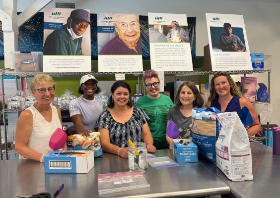 Board members posing for a picture while bagging pet food.